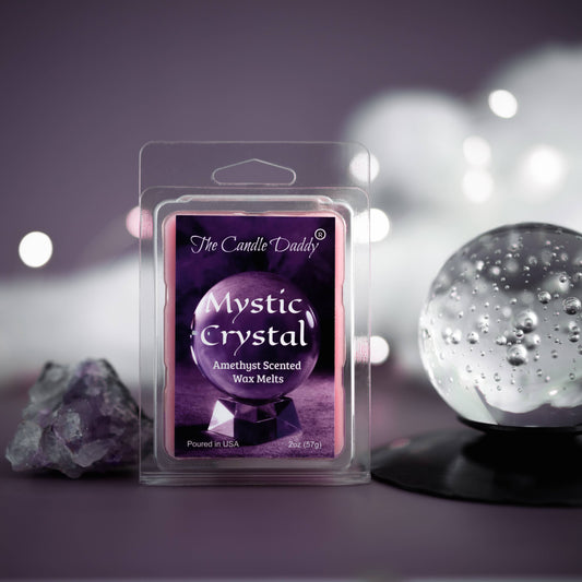 A packaged 'Mystic Crystal' amethyst scented wax melt by The Candle Daddy, with a purple label and a clear plastic cover, displayed next to a crystal ball and decorative lights.